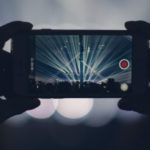 Person holding iPhone at concert to record video