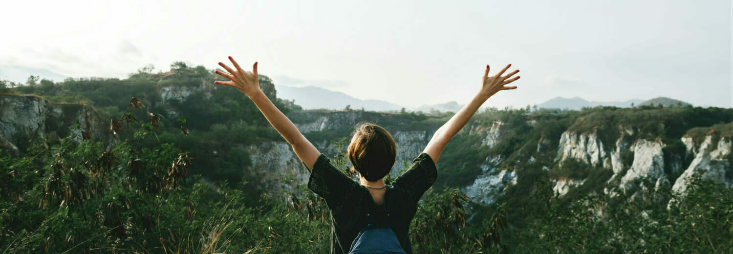 Woman standing at top of mountain with arms in the air