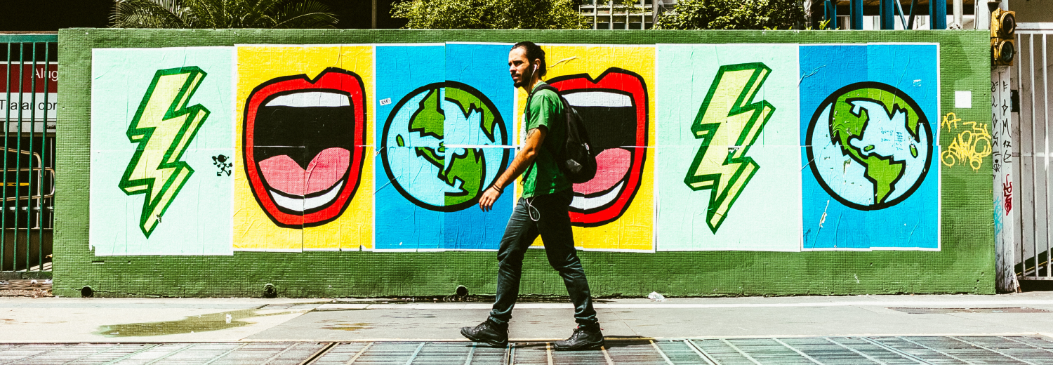 Man walking down street beside colorful street art