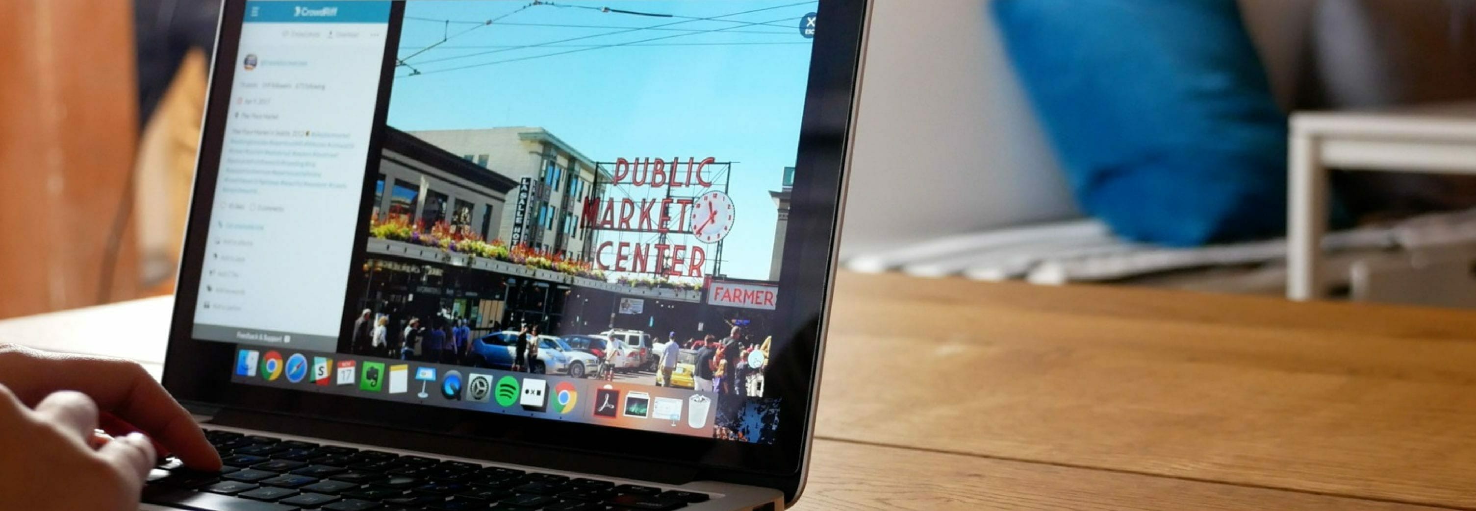 Person working on macbook on table, CrowdRiff platform on the screen with image of Public Market Center in Seattle selected