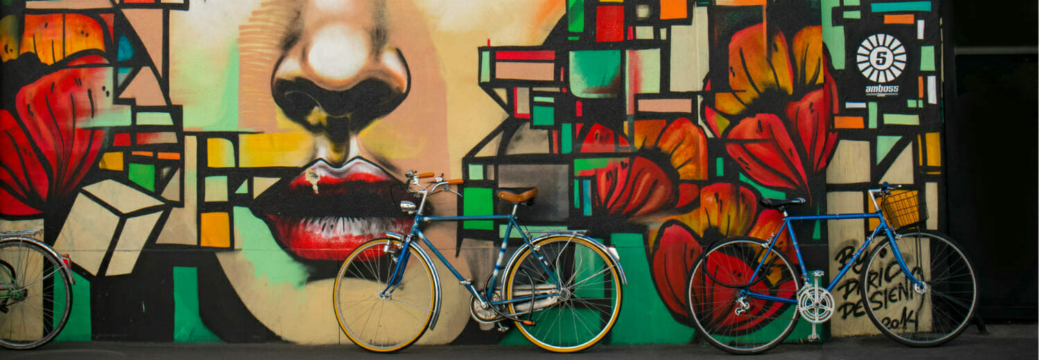 Bikes leaning up against a colourful graffiti wall