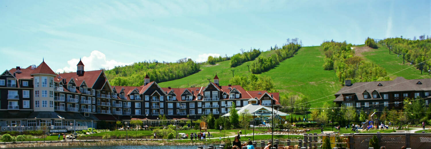 Blue Mountain village in the summertime. View of village, hotels, and grassy hill.