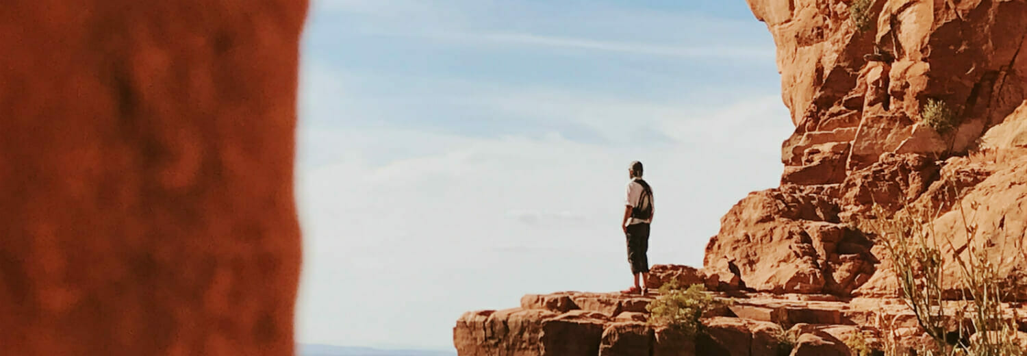 Man on mountain in desert staring out into the distance