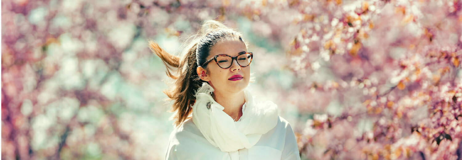 Girl wearing glasses with cherry blossoms in the background