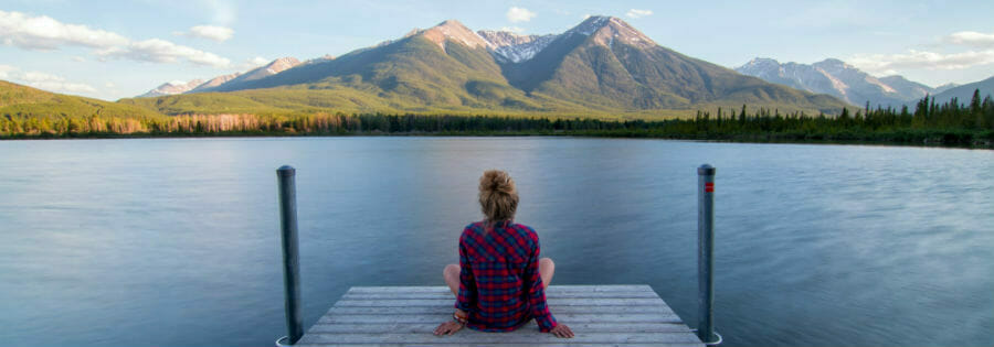 Girl sitting on dock on lake in the mountains